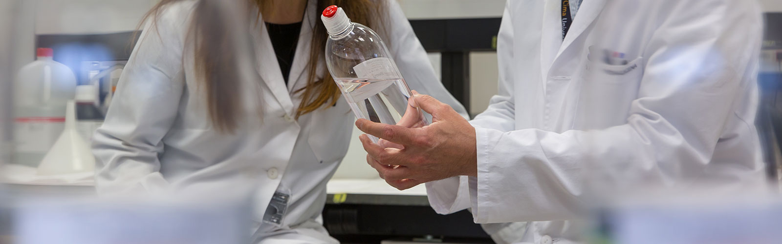 investgadores analizando el contenido líquido de un frasco, en el Cima Universidad de Navarra